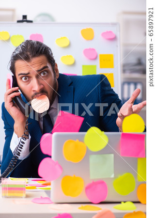 Young male employee in conflicting priorities concept 65897921