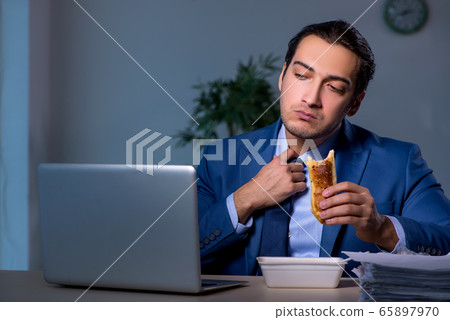 Hungry employee working late in the office Hungry employee working late in the office 65897970