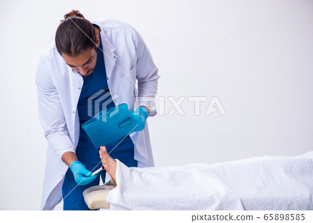 Police coroner examining dead body corpse in morgue 65898585