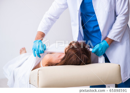 Police coroner examining dead body corpse in morgue 65898591