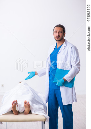 Police coroner examining dead body corpse in morgue 65898592