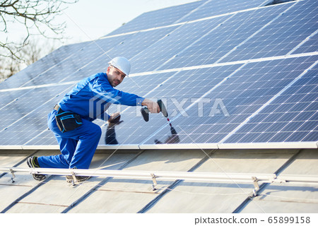 Electrician mounting solar panel on roof of modern house Electrician mounting solar panel on roof of modern house 65899158