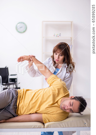 Injured man visiting young female doctor osteopath Injured man visiting young female doctor osteopath 65899285