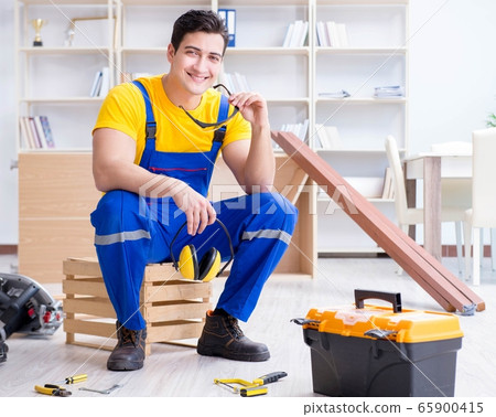 Young contractor doing repair works at office Young contractor doing repair works at office 65900415