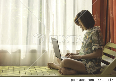 Women work with notebooks on the wooden bed  Background white curtains and natural light. 65900417