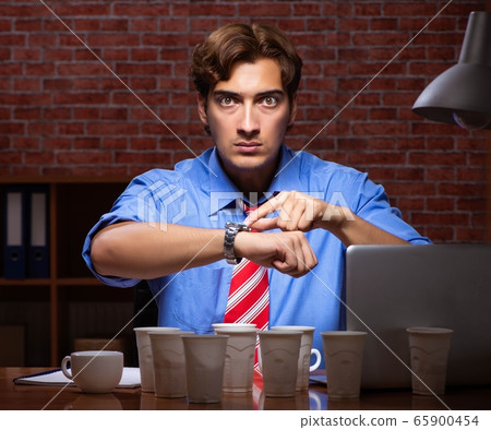 Young employee drinking coffee working at night shift 65900454