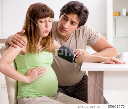 Husband checking pregnant wife's blood pressure 65901272