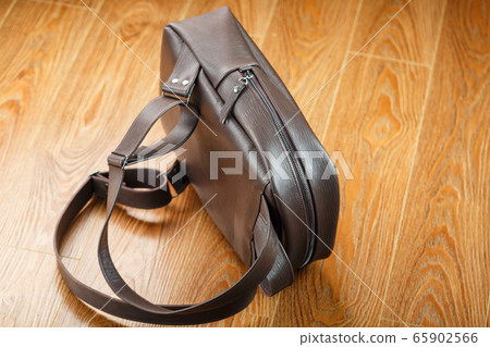 Backpack made of brown genuine leather on a wooden Backpack made of brown genuine leather on a wooden 65902566