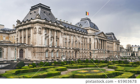 The Royal Palace in Brussels, Belgium from the northeastern corner in spring. National flag of the Kingdom of Belgium waving on top. 65903678