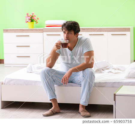 Young handsome man drinking coffee in the bed Young handsome man drinking coffee in the bed 65903758