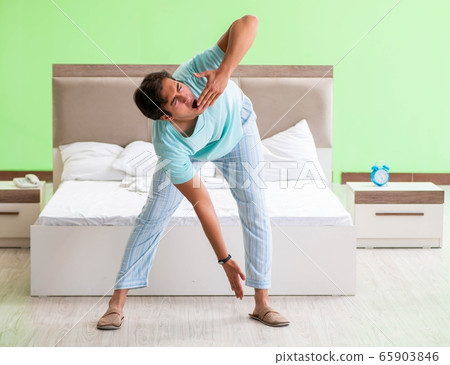 Young man in pajamas doing morning exercises 65903846
