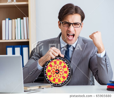 Businessman with dartboard sitting at the office 65903880