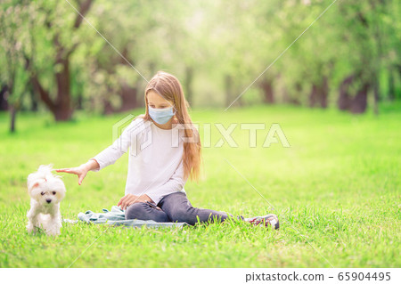 Little girl with dog wearing protective medical mask for prevent virus outdoors in the park 65904495