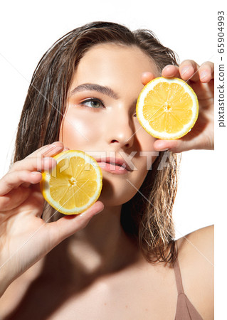 Citrus. Close up of beautiful female face with lemon slices over white background. Cosmetics and makeup, natural and eco treatment, skin care. Citrus. Close up of beautiful female face with lemon slices over white background. Cosmetics and makeup, natural and eco treatment, skin care. 65904993
