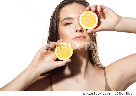 Citrus. Close up of beautiful female face with lemon slices over white background. Cosmetics and makeup, natural and eco treatment, skin care. 65904995