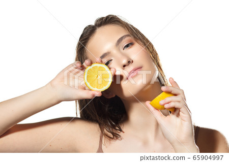 Citrus. Close up of beautiful female face with lemon slices over white background. Cosmetics and makeup, natural and eco treatment, skin care. Citrus. Close up of beautiful female face with lemon slices over white background. Cosmetics and makeup, natural and eco treatment, skin care. 65904997