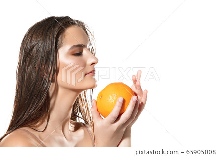 Close up of beautiful female face with orange over white background. Cosmetics and makeup, natural and eco treatment, skin care. 65905008