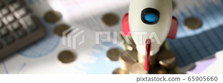 Toy space rocket stands on coins near calculator Toy space rocket stands on coins near calculator 65905660