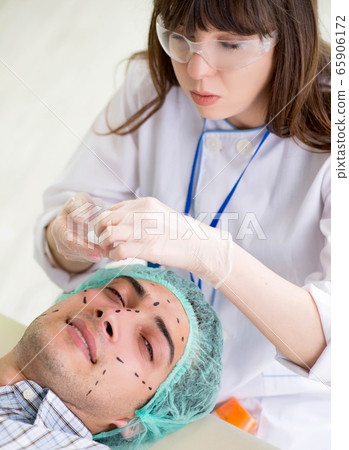 Plastic surgeon preparing for operation on man face 65906172