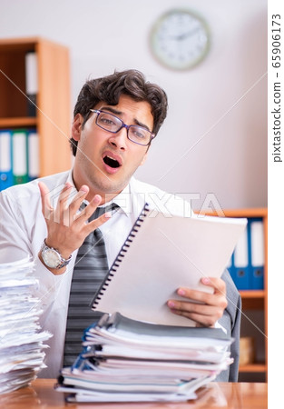 Young handsome businessman unhappy with excessive work 65906173