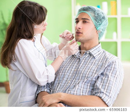 Plastic surgeon preparing for operation on man face Plastic surgeon preparing for operation on man face 65906183