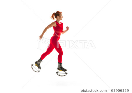 Beautiful redhead woman in a red sportswear jumping in a kangoo jumps shoes isolated on white studio background. 65906339
