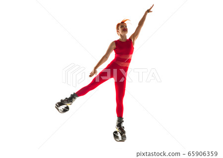 Beautiful redhead woman in a red sportswear jumping in a kangoo jumps shoes isolated on white studio background. 65906359