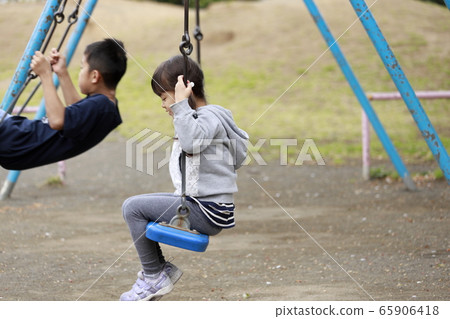 Brother and sister playing on a swing (10 and 5 years old) Brother and sister playing on a swing (10 and 5 years old) 65906418