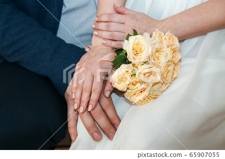 hands of the newlyweds with a wedding bouquet hands of the newlyweds with a wedding bouquet 65907055