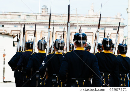 Unidentified soldiers marching in a changing of the guard in old military uniforms Unidentified soldiers marching in a changing of the guard in old military uniforms 65907371