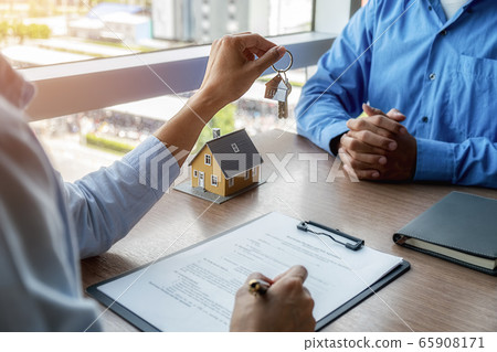 Estate agent holding a key and asking costumer for contract to buy, get insurance or loan estate. 65908171