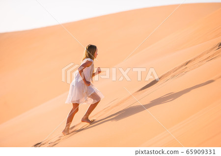 Girl among dunes in desert in United Arab Emirates 65909331