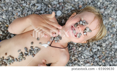 On sunny beach kids lying on pebble, warming after On sunny beach kids lying on pebble, warming after 65909630