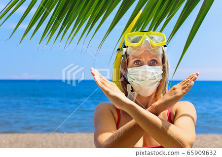 Funny girl in surgical face mask on sea beach Funny girl in surgical face mask on sea beach 65909632