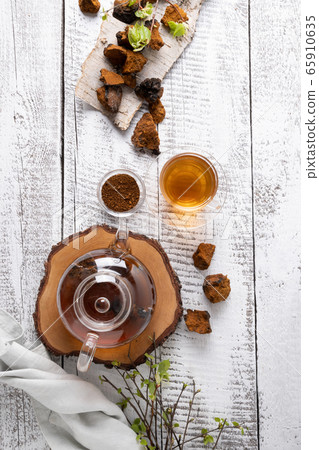 Chaga mushrooms infusion in glass teapot on white. 65910635