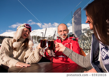 Group of happy friends cheering with drink after skiing day in cafe at ski resort. 65910816