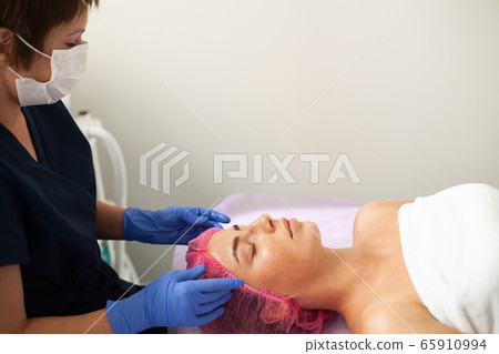 Woman getting LPG hardware massage at the beauty clinic. Professional beautician working. Woman getting LPG hardware massage at the beauty clinic. Professional beautician working. 65910994