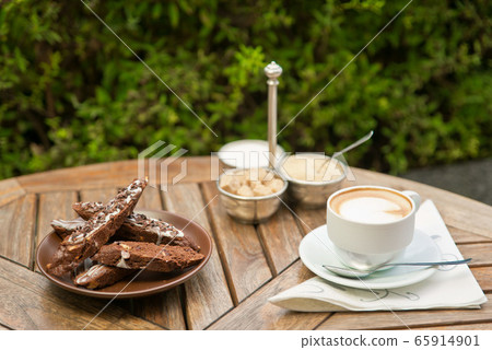 a plate of homemade biscotti cookies and a Cup of coffee with cream and sugar on the wooden table. Blurred background 65914901