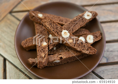 chocolate Homemade biscotti with nuts on a brown plate on a wooden table chocolate Homemade biscotti with nuts on a brown plate on a wooden table 65914910