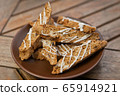 homemade Biscotti with nuts and white chocolate on a brown plate on a wooden table 65914921