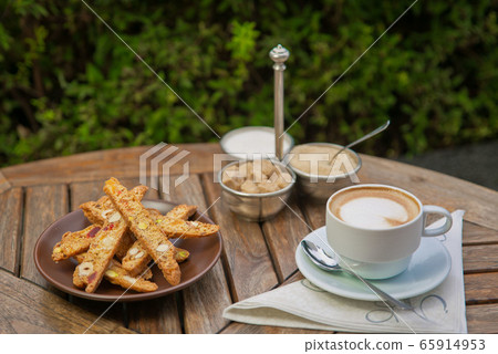 a plate of homemade biscotti cookies and a Cup of coffee with cream and sugar on the wooden table. Blurred background 65914953