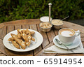 a plate of homemade biscotti cookies and a Cup of coffee with cream and sugar on the wooden table. Blurred background 65914954