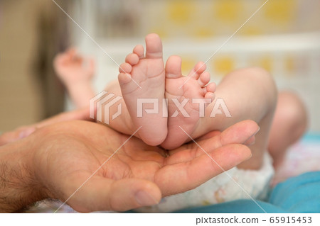 Baby feet in parent hands. Father and her child. Feet of newborn baby. Parenthood concept. 65915453