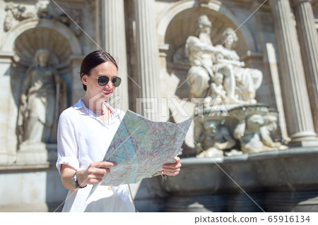 Young woman with a city map in city. Travel tourist girl with map in Vienna outdoors during holidays in Europe. Young woman with a city map in city. Travel tourist girl with map in Vienna outdoors during holidays in Europe. 65916134