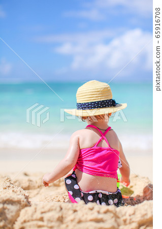 Little girl at tropical white beach making sand castle Little girl at tropical white beach making sand castle 65916708