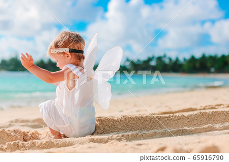 Beautiful young girl wearing angel wings on the beach Beautiful young girl wearing angel wings on the beach 65916790
