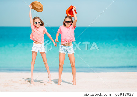 Little happy funny girls have a lot of fun at tropical beach playing together. Little happy funny girls have a lot of fun at tropical beach playing together. 65918028