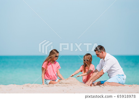 Father and kids making sand castle at tropical beach. Family playing with beach toys 65918978