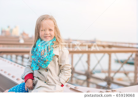 Adorable little girl sitting at Brooklyn Bridge in New York Adorable little girl sitting at Brooklyn Bridge in New York 65919068