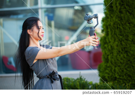Blogger girl shoots a video about traveling on an electronic stabilizer. Blogger girl shoots a video about traveling on an electronic stabilizer. 65919207